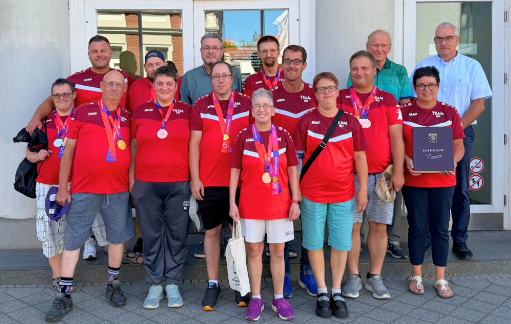 Das erfolgreiche Team der Rathenower Werkstätten gGmbH gemeinsam mit Betreuenden und Trainern der SG Medizin und dem Ersten Beigeordneten Matthias Remus vor dem Rathenower Rathaus anlässlich ihres Eintrags ins Ehrenbuch der Stadt